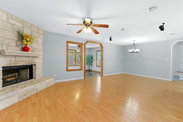 unfurnished living room featuring a fireplace, light hardwood / wood-style flooring, and ceiling fan with notable chandelier