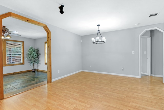 empty room with ceiling fan with notable chandelier and light tile flooring