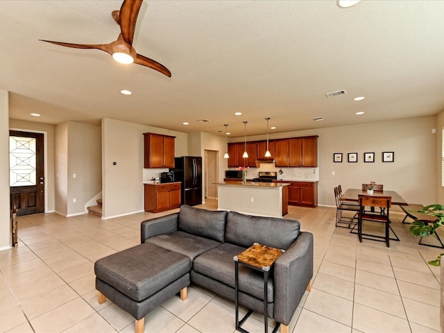 living room featuring ceiling fan, a textured ceiling, and light tile flooring