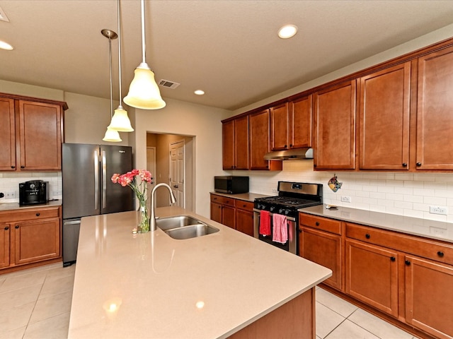 kitchen with a center island with sink, stainless steel appliances, decorative light fixtures, sink, and light tile floors