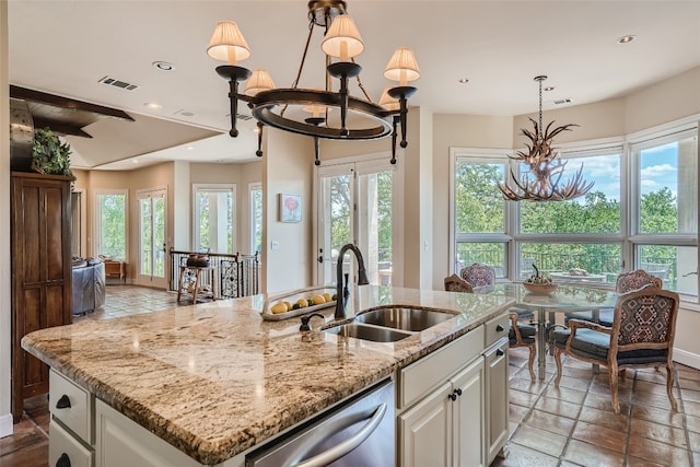 kitchen with decorative light fixtures, white cabinets, dishwasher, a center island with sink, and sink