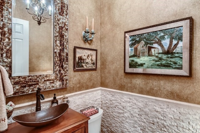 bathroom featuring an inviting chandelier, oversized vanity, and toilet