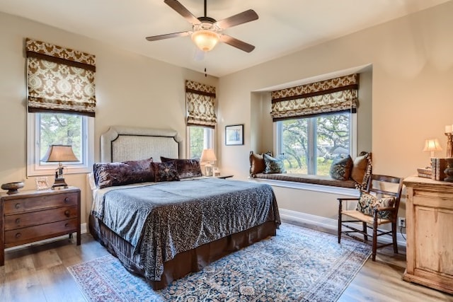 bedroom with ceiling fan, light wood-type flooring, and multiple windows