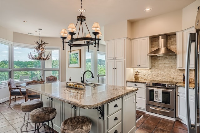 kitchen with tasteful backsplash, stainless steel electric stove, an island with sink, wall chimney exhaust hood, and sink