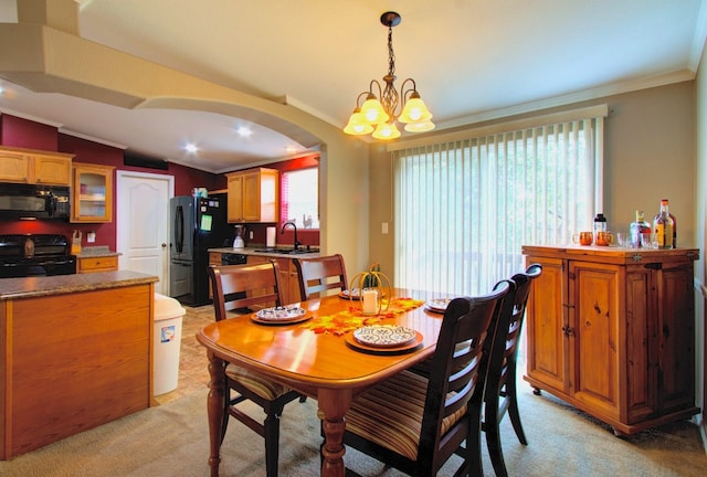 carpeted dining room featuring lofted ceiling, ornamental molding, an inviting chandelier, and sink