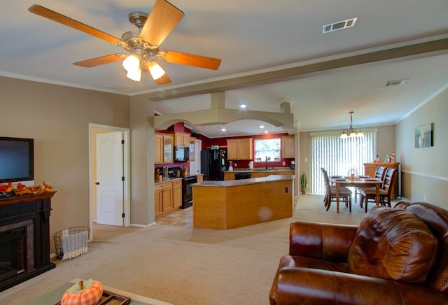 living room featuring ceiling fan with notable chandelier, light colored carpet, ornamental molding, and sink