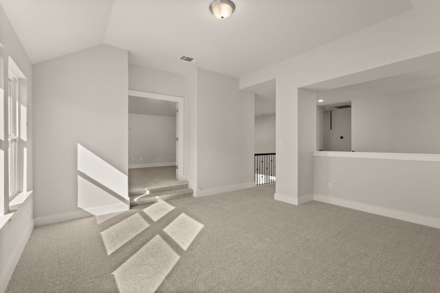 spare room with light colored carpet and lofted ceiling