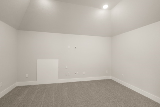 carpeted empty room with lofted ceiling