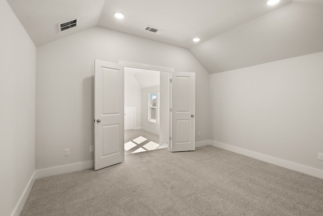 additional living space with light colored carpet and vaulted ceiling