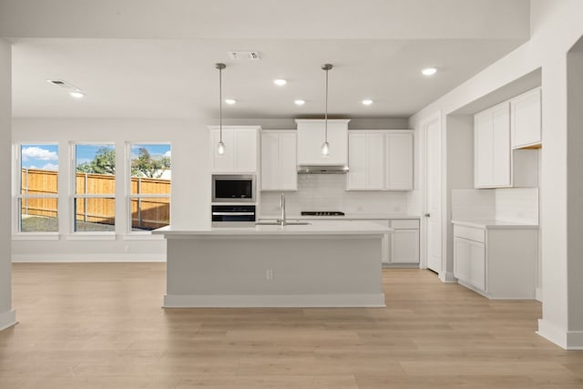 kitchen featuring white cabinets, a center island with sink, and appliances with stainless steel finishes