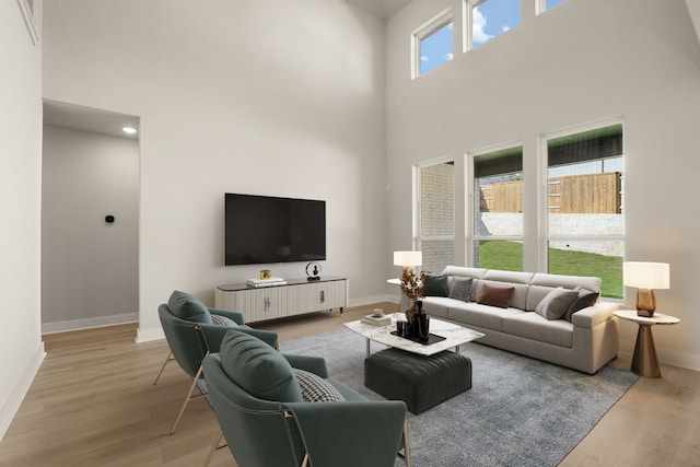 living room featuring plenty of natural light, light hardwood / wood-style floors, and a high ceiling