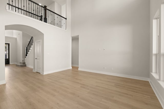 unfurnished living room with light wood-type flooring and a high ceiling