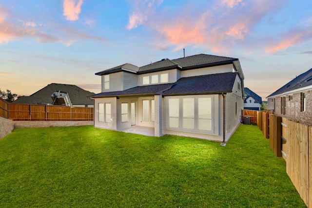 back house at dusk with a yard and a patio