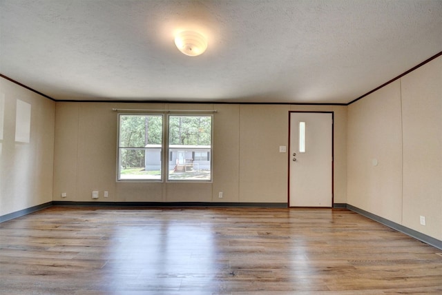 spare room featuring a textured ceiling, ornamental molding, and hardwood / wood-style floors