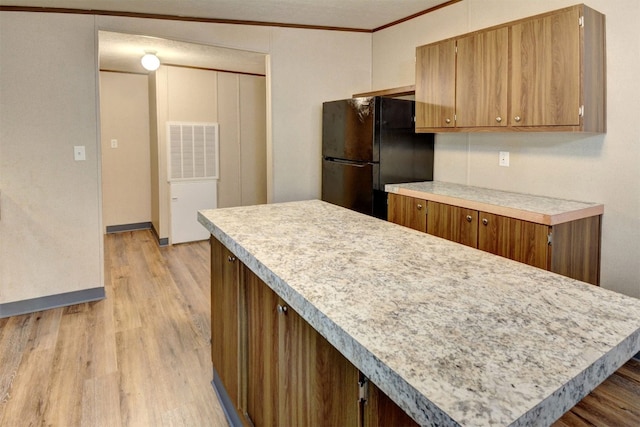 kitchen with light hardwood / wood-style floors, crown molding, and black fridge