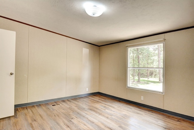 spare room featuring crown molding and light wood-type flooring