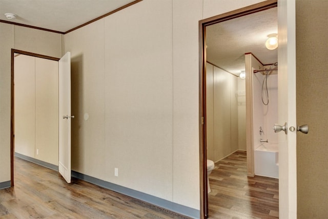 unfurnished bedroom featuring a textured ceiling, ornamental molding, and wood-type flooring