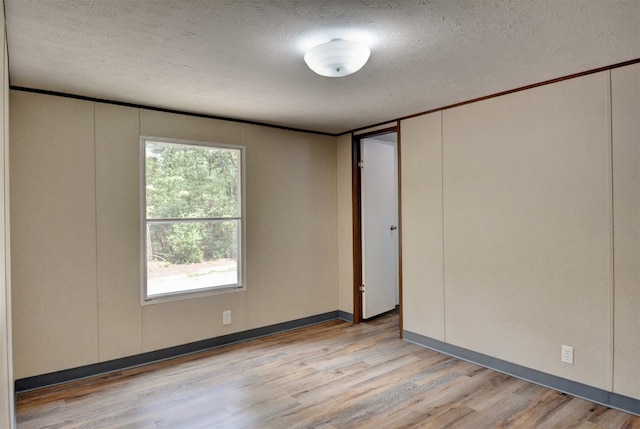 unfurnished room with light hardwood / wood-style flooring and a textured ceiling