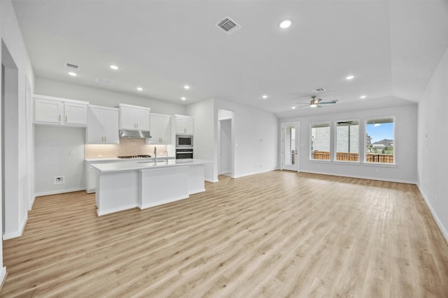 kitchen featuring appliances with stainless steel finishes, light wood-type flooring, white cabinetry, and an island with sink