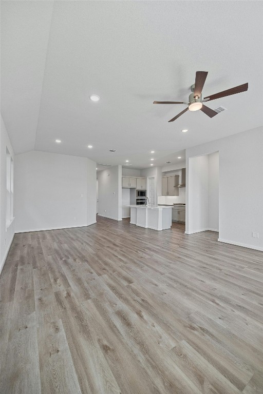 unfurnished living room with ceiling fan and light hardwood / wood-style floors