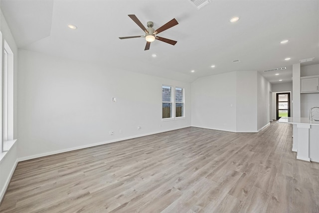 unfurnished living room featuring ceiling fan, light hardwood / wood-style floors, sink, and vaulted ceiling