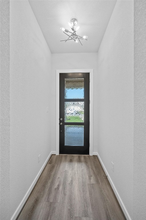 doorway to outside featuring hardwood / wood-style floors and a notable chandelier