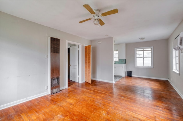 unfurnished living room featuring ceiling fan, a wall mounted air conditioner, and light hardwood / wood-style flooring