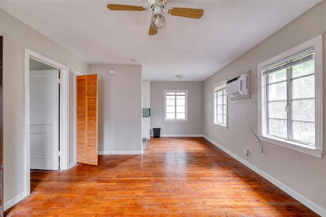 unfurnished room featuring ceiling fan, a wall mounted AC, light hardwood / wood-style floors, and a wealth of natural light