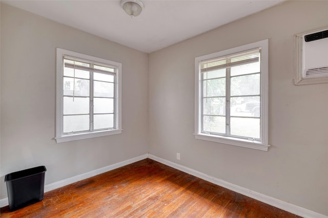 unfurnished room featuring dark wood-type flooring and a wall unit AC