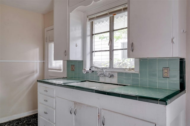 kitchen featuring white cabinetry, sink, backsplash, and tile counters