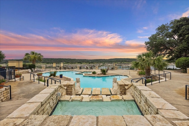 pool at dusk featuring a patio area and pool water feature