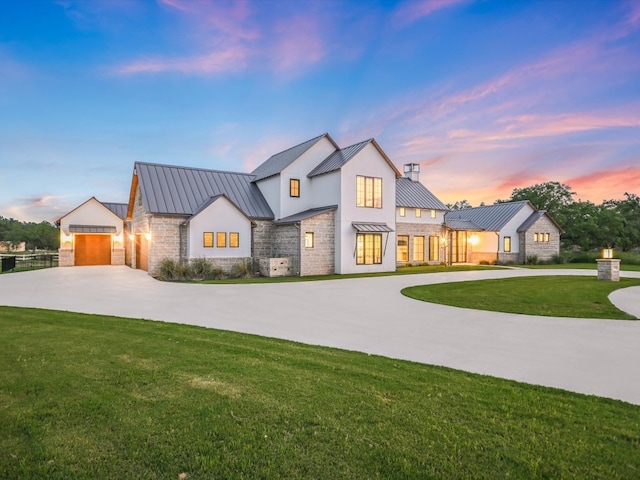 modern inspired farmhouse featuring a garage and a lawn