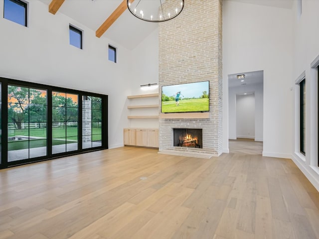 unfurnished living room featuring high vaulted ceiling, brick wall, and light wood-type flooring