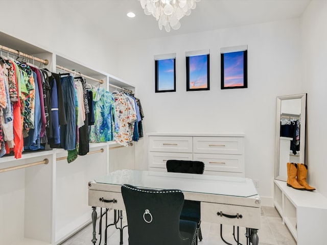 walk in closet with an inviting chandelier and light tile floors