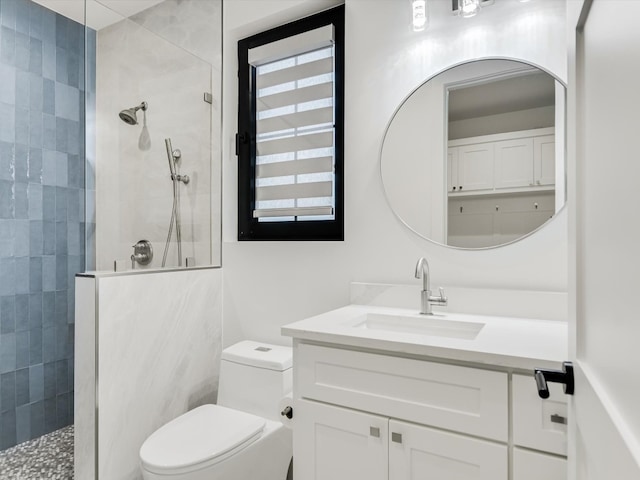 bathroom featuring a tile shower, toilet, and vanity