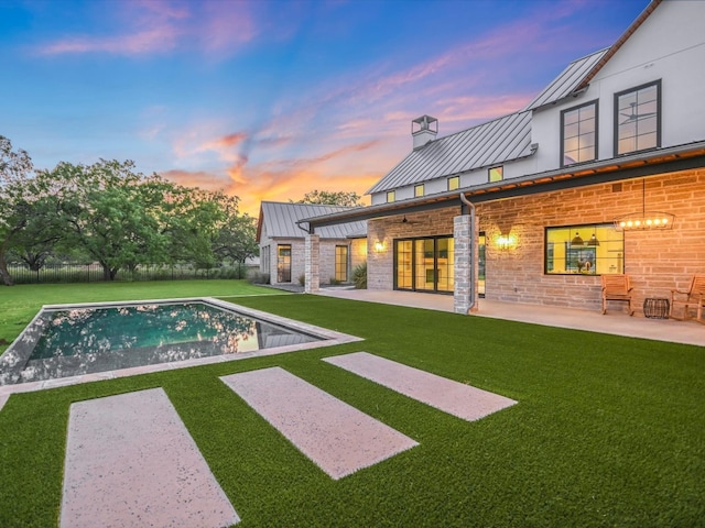 pool at dusk with a yard and a patio