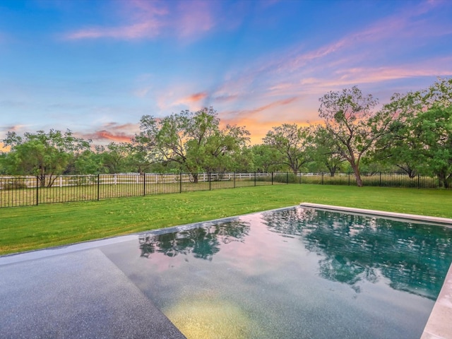 pool at dusk featuring a yard