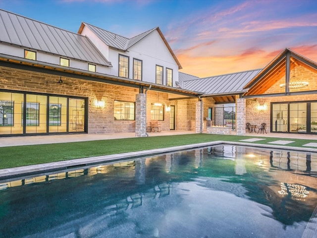 pool at dusk featuring a patio