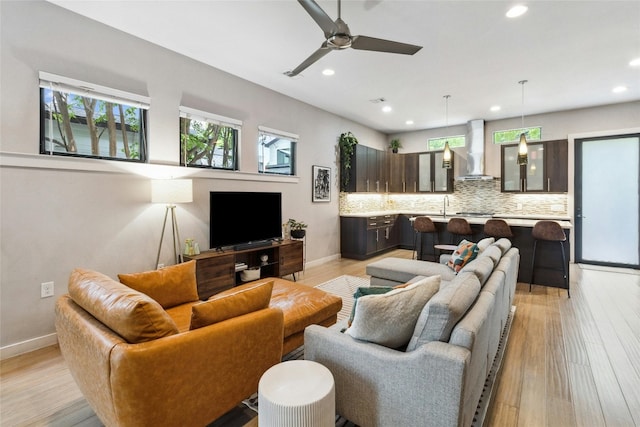 living room with sink, ceiling fan, and light hardwood / wood-style flooring