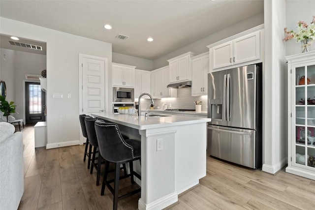 kitchen with white cabinetry, appliances with stainless steel finishes, sink, and a kitchen island with sink