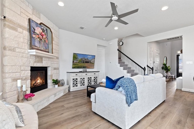 living room with a fireplace, light hardwood / wood-style flooring, and a textured ceiling