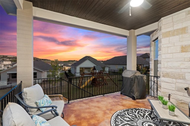 patio terrace at dusk featuring ceiling fan, area for grilling, and a balcony