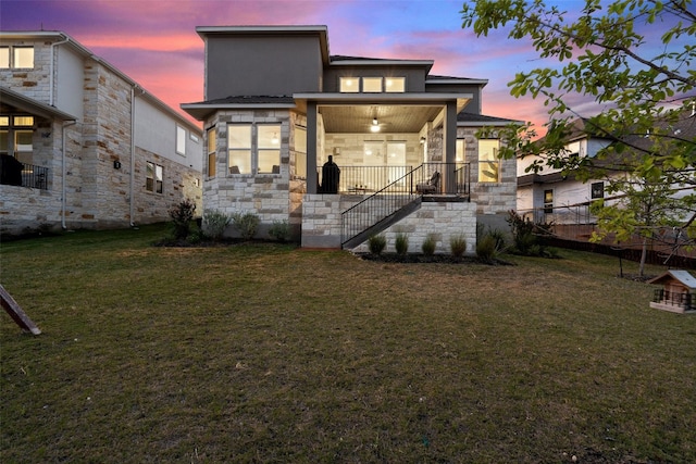 back house at dusk featuring a lawn