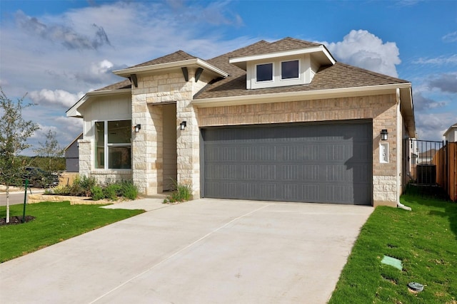 view of front of property with a front yard, a garage, and central air condition unit