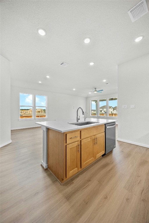 kitchen with dishwasher, a center island with sink, light hardwood / wood-style floors, and sink