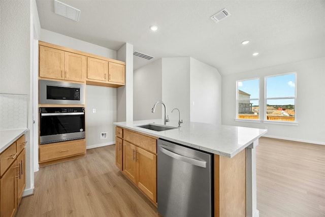 kitchen featuring a center island with sink, sink, light hardwood / wood-style flooring, light stone counters, and stainless steel appliances