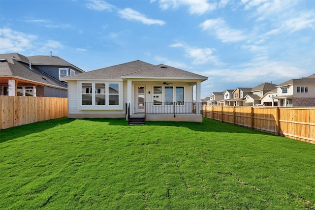 back of property featuring ceiling fan and a yard