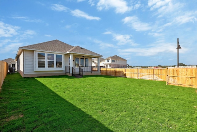 rear view of property featuring central air condition unit, ceiling fan, and a lawn