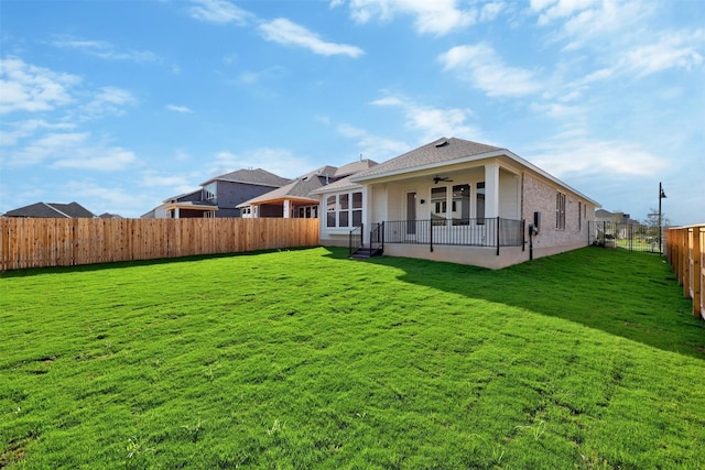 back of property featuring ceiling fan and a lawn