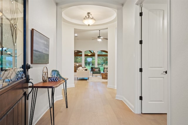 corridor with a raised ceiling and light hardwood / wood-style flooring